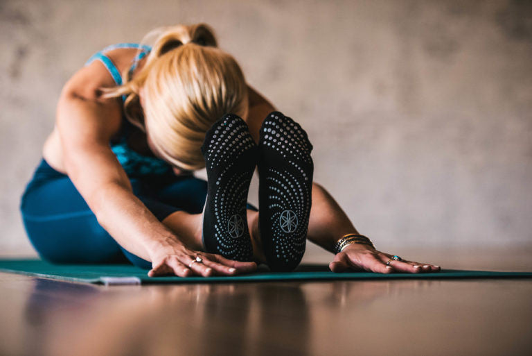 Blonde woman does seated forward fold in yoga socks