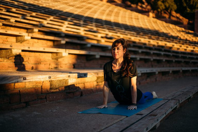 Woman on a teal yoga mat outside 