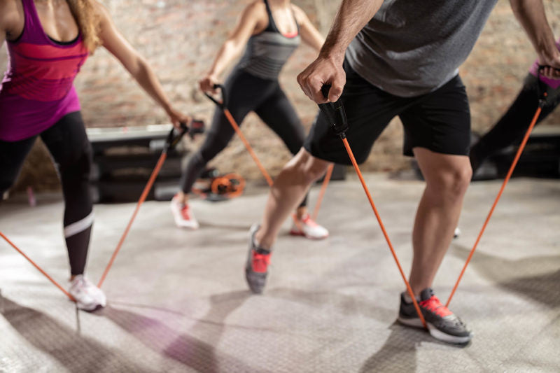 Four people working out with red resistance bands