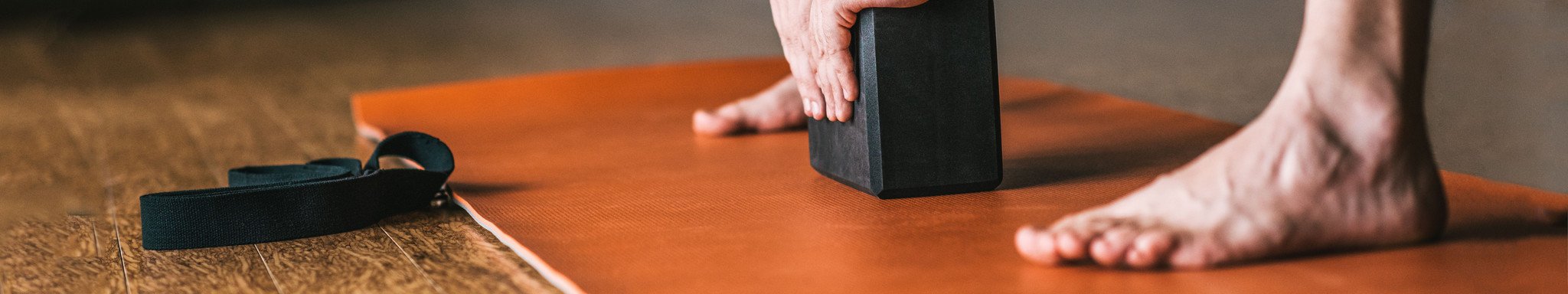 man on yoga mat using a block