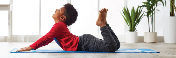 Happy child laying on meditation cushion in child's pose