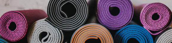 Many colorful yoga mats stacked on top of one another.