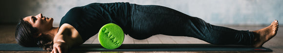 Woman laying on top of green foam roller.