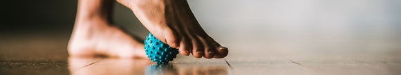 person rolling the ball of their foot on a blue massage ball
