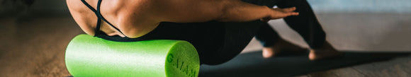 Woman rolling her back on green foam roller