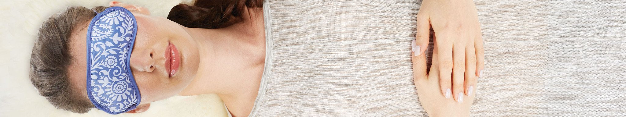 Top view of a woman laying down with eyes covered with eye pillow.