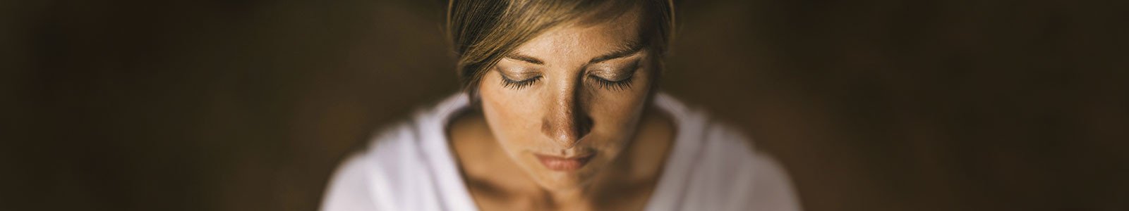 Peaceful woman meditating with eyes closed.
