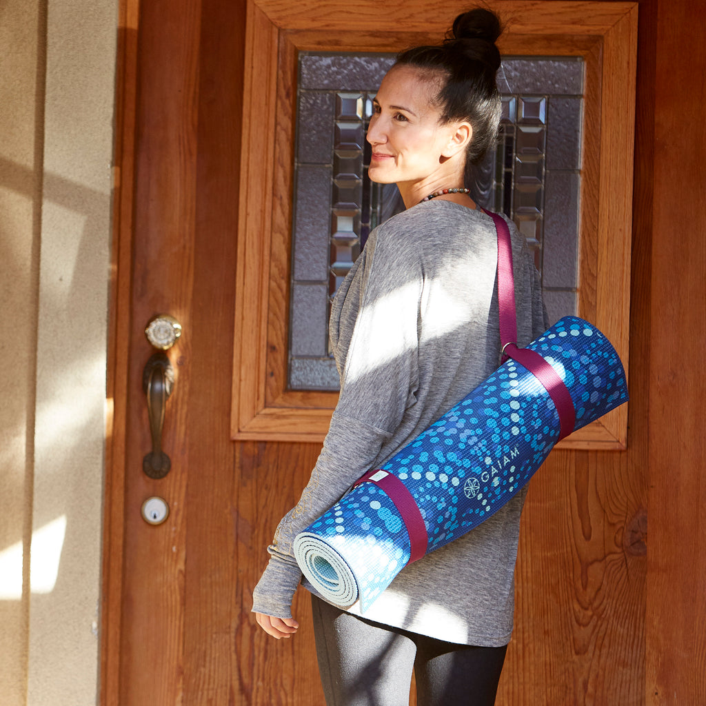 Woman carry yoga mat with carrying strap over her shoulder