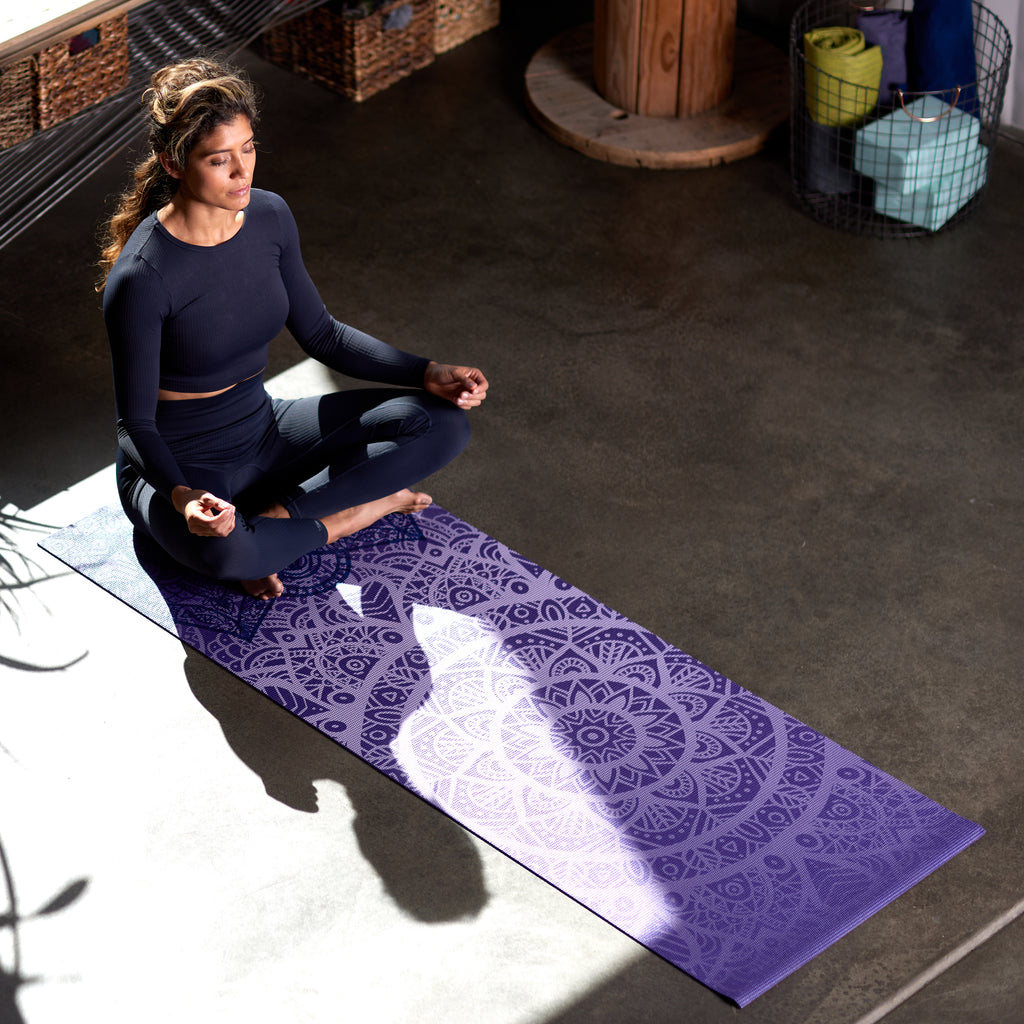 Person seated on Yoga Mat in Lotus Pose.