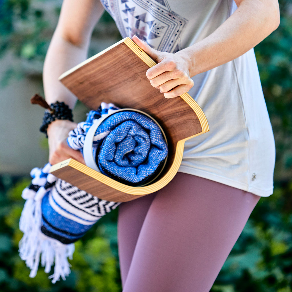 Woman placing the rolled up meditation blanket beneath the meditation bench